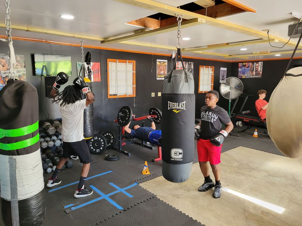 A boxer throwing punches at a heavy bag on the gym floor