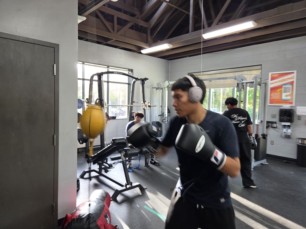 A boxer working the bag on the training floor, headphones on